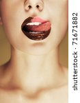 Close-up shot of beautiful woman lips with chocolate, girl licking her lips. Conceptual image. - stock photo