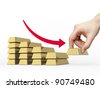 Decrease bar chart made of golden bars. Hand take off the bottom bar. Red arrow shows decrease. - stock photo
